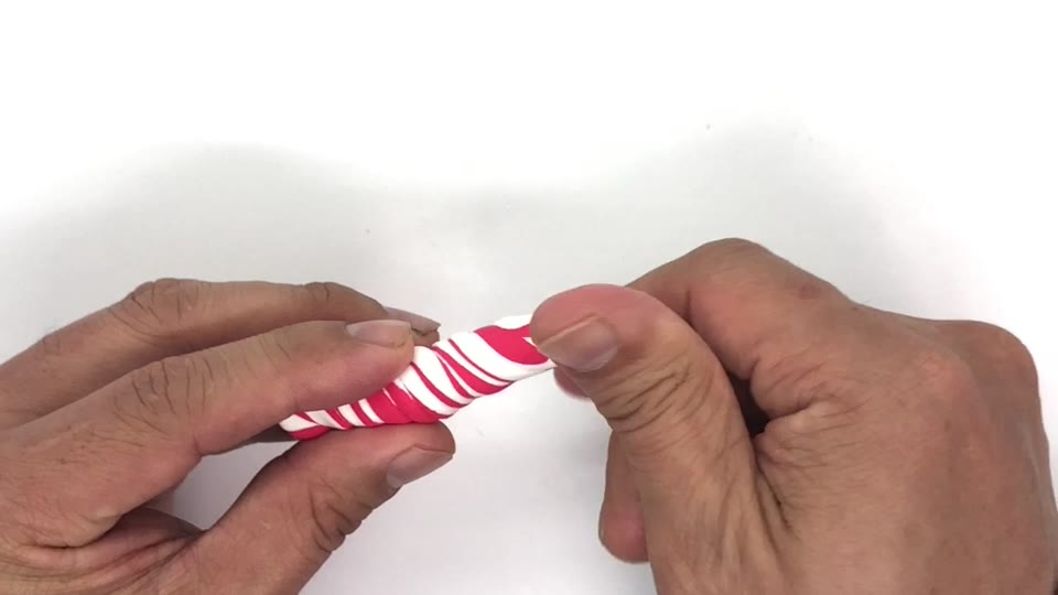赤と白をねじった粘土をのばす手元